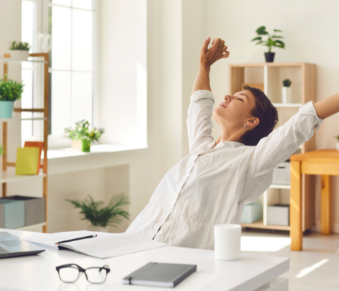 woman sitting at desk taking a stretch