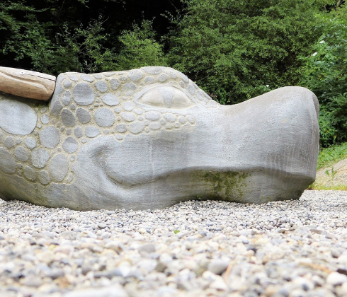 woman laying down, facing stone statue of dragon