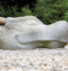 woman laying down, facing stone statue of dragon